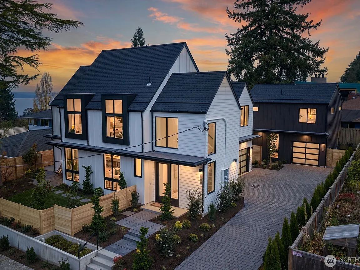 Two-story gabled home with light siding, dark upper walls and an attached garage